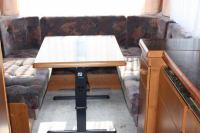 Hobby 495 внутри автомобильного прицепа - стол, вокруг мягкие кресла и обеденный стол Hobby 495 внутри автомобильного прицепа - стол, вокруг мягкие кресла и обеденный стол